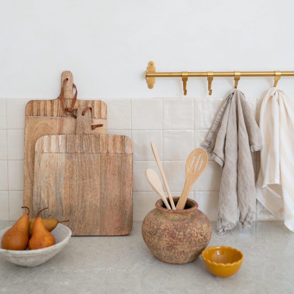 Interior kitchen stock image featuring wood cutting boards, utensils, bowl of pears and hanging towels. Stock images for female entrepreneurs.