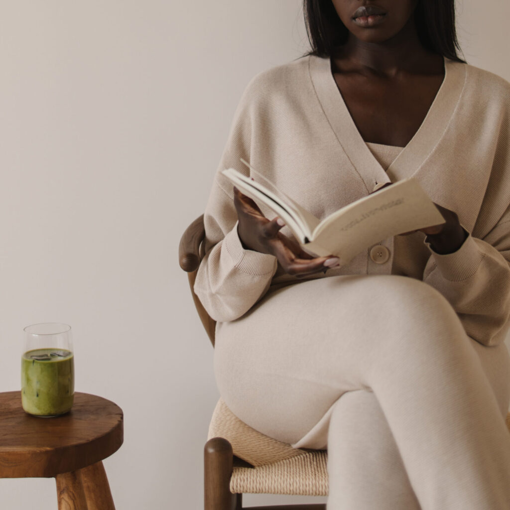 Editorial stock images for brands and businesses looking for workspace images featuring woman reading a book while drinking iced matcha.