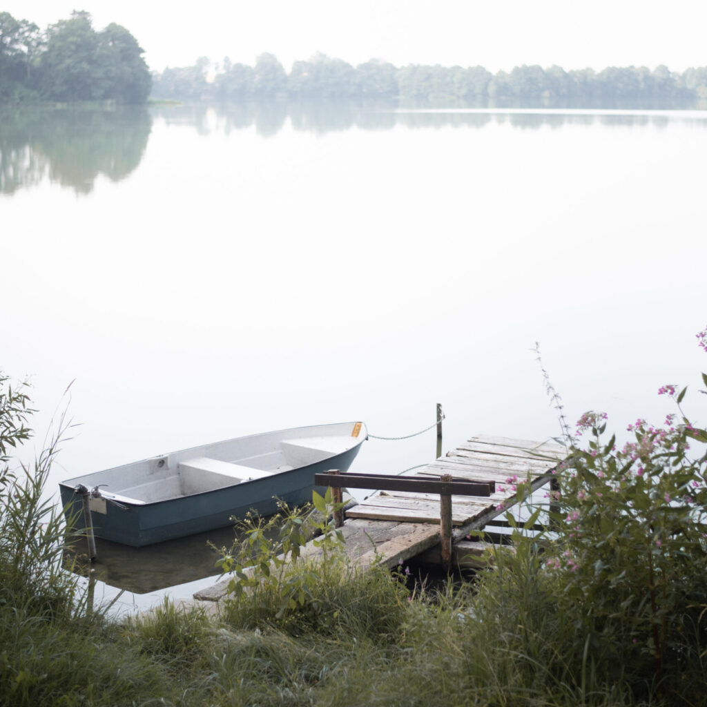 Calming Stock photo featuring a serene view of a boat moored on a calm lake