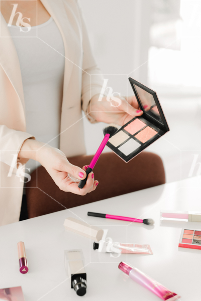 Stock photo by Haute Stock showing woman holding blush palette with brushes on table