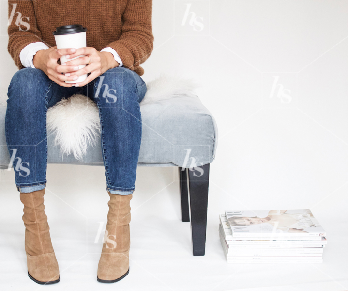 Stock image of woman in jeans and brown sweater with coffee cup.