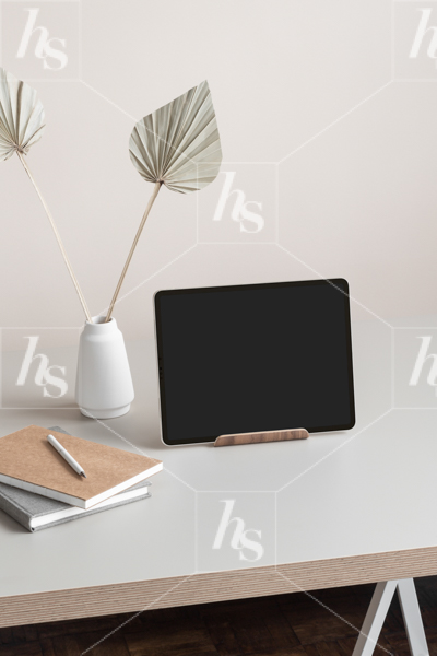 Styled mockup photo featuring an iPad, notebooks and Palms in white vase on desk