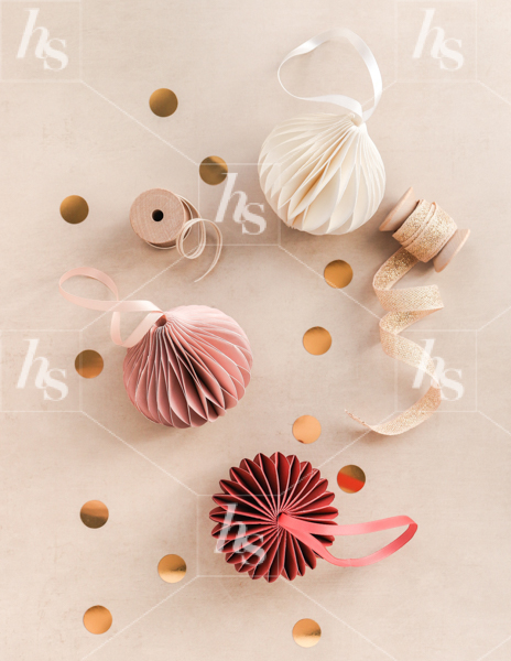 Flatlay image of red and pink paper ornaments on taupe background