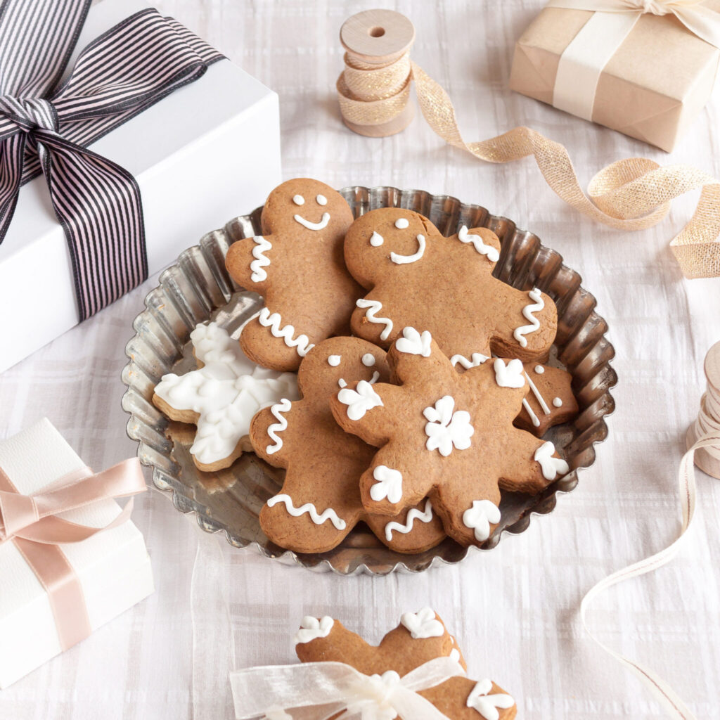 Stock image of ginger bread cookies next to wrapped presents and ribbons in neutral colors