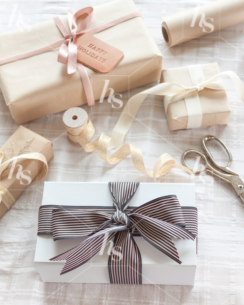 Holiday stock image featuring neutral color wrapped presents, ribbons and scissors