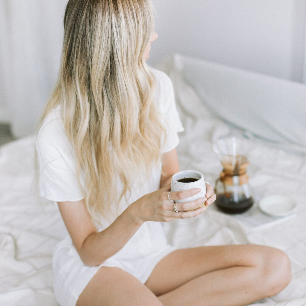 Lifestyle stock photography featuring a blonde woman having fresh cup of coffee on the bed