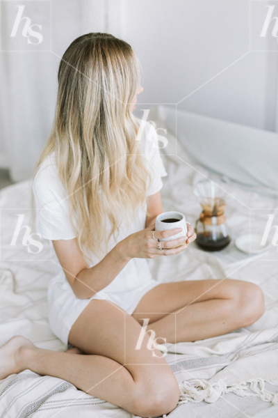 Styled lifestyle stock image of blonde woman having coffee in bed