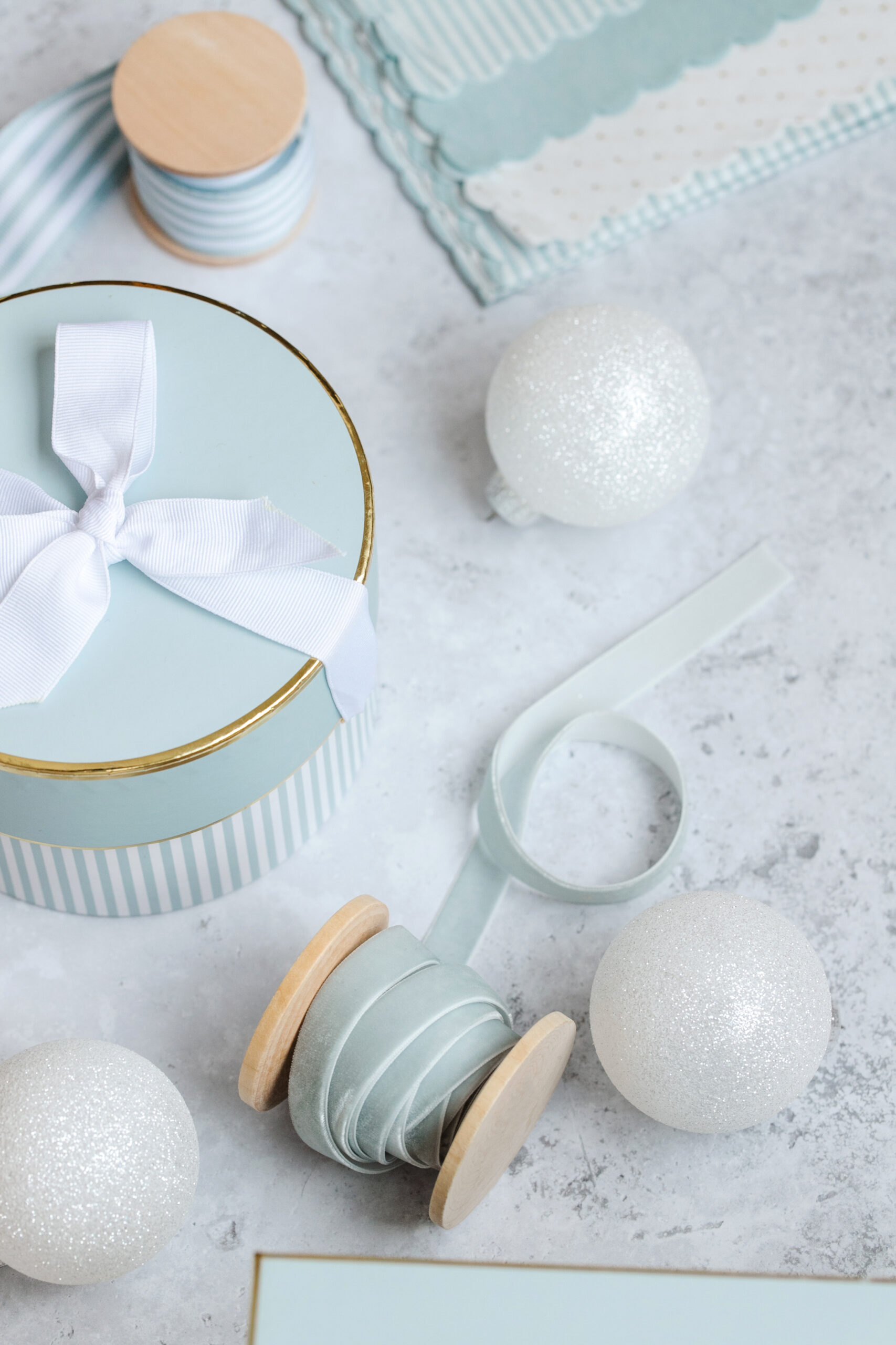 Blue styled holiday stock image featuring vintage gift box, blue ribbon and white ornaments on marble background