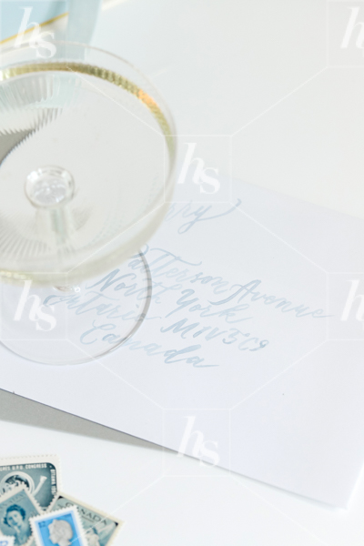Champagne glass on a hand written letter, a styled stock image by Haute Stock