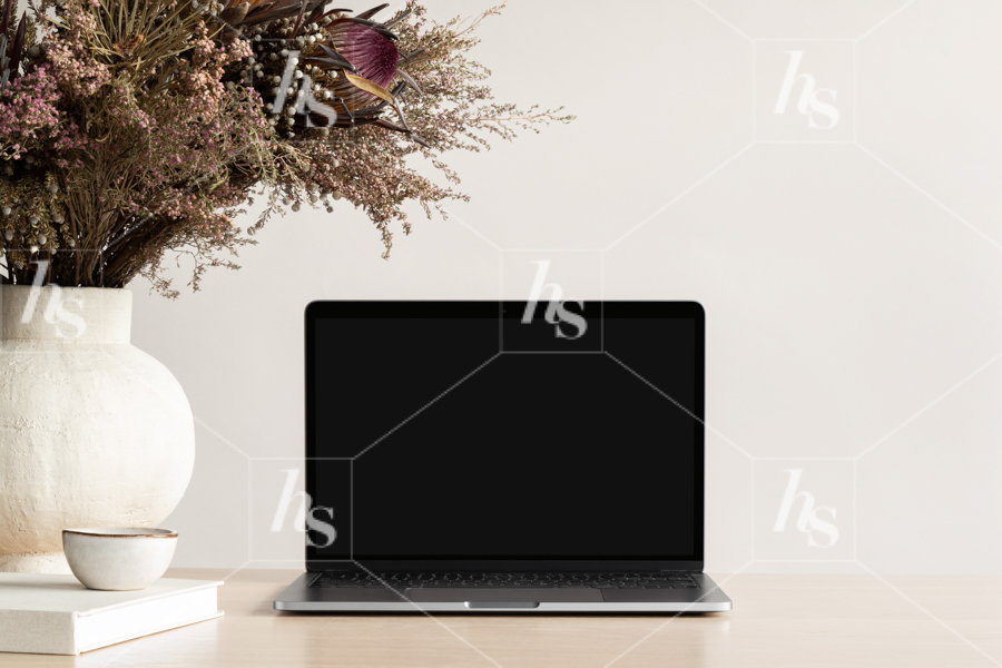 Laptop mockup on desk next to large bouquet of foliage and florals perfect  for social media and brand designs