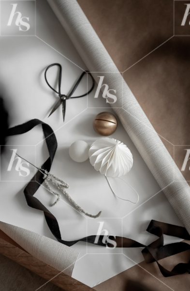 Ornaments and black ribbon on wrapping paper on brown background by Haute Stock