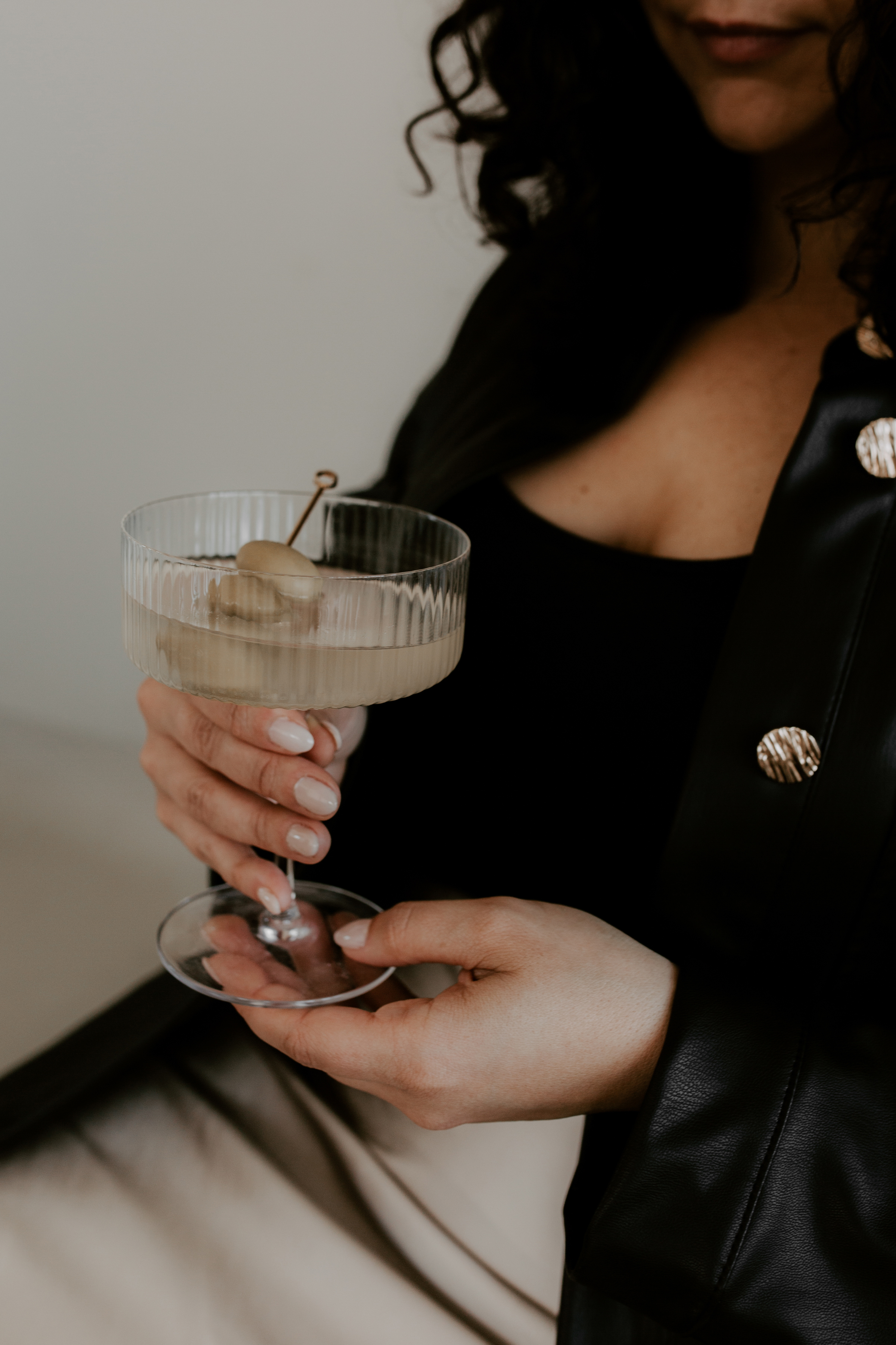 Minimal stock photo of woman dressed in black holding a martini glass