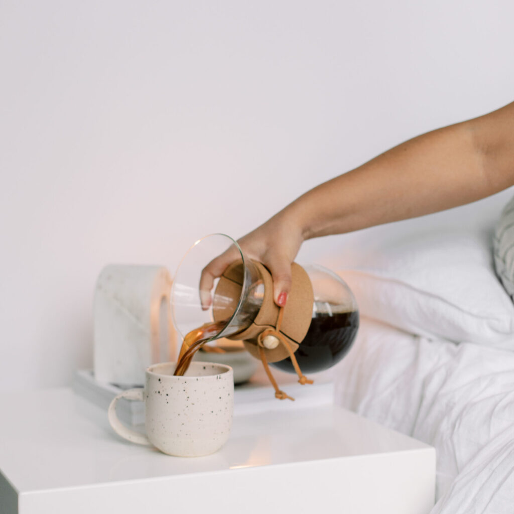 Stock image of woman pouring a cup of coffee while in bed, perfect for wellness and lifestyle bloggers