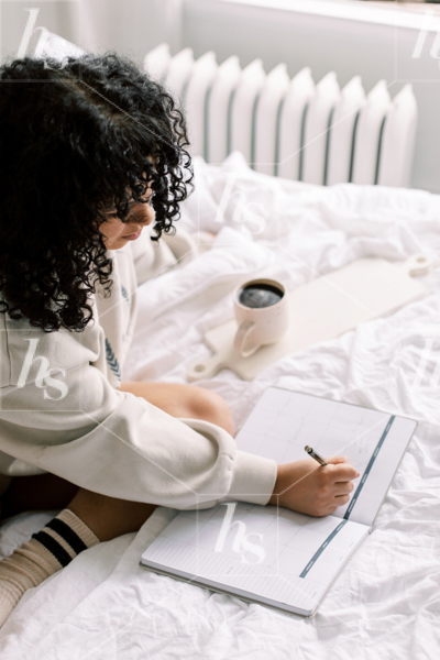 This stock photo by Haute Stock features a woman writing in journal on cozy bed.