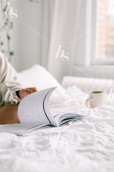 Styled stock photo of woman working on bed, perfect for working from home imagery