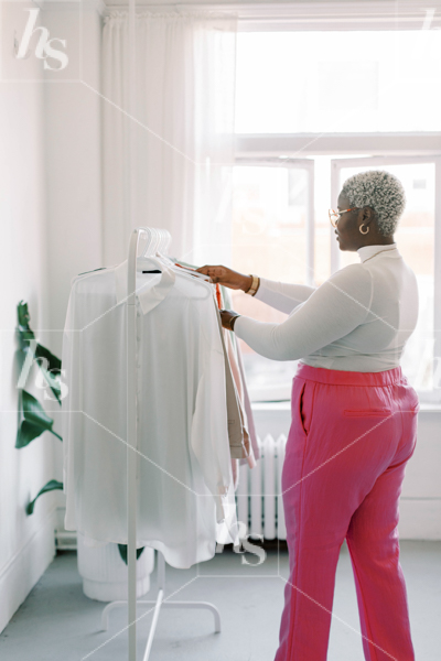 Stock image for fashion bloggers and life coaches, featuring plus size model browsing through clothes on rack