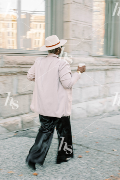 Stock photo featuring woman walking downtown while drinking coffee
