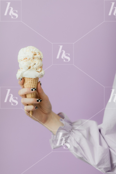 Stock photo of woman holding ice cream cone against a purple background