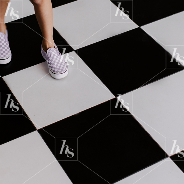 Girl stepping on black and white checkered floor, playful images for spring and summer brands.