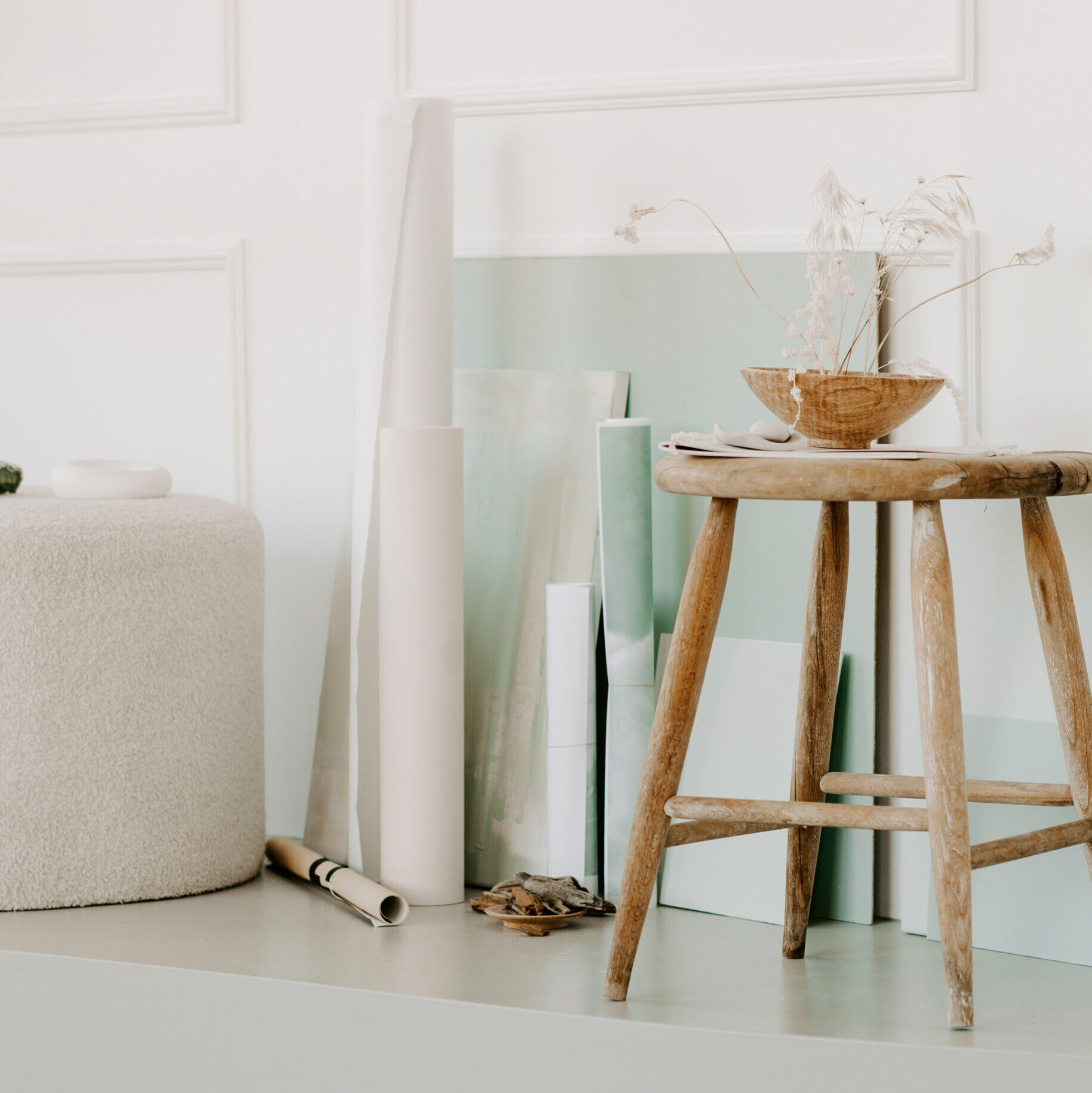 Stock photo of an artist's studio with a wooden stool and mint collared canvases.
