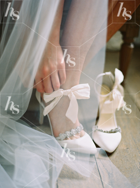 Stylish wedding stock photo of a bride adjusting her shoe
