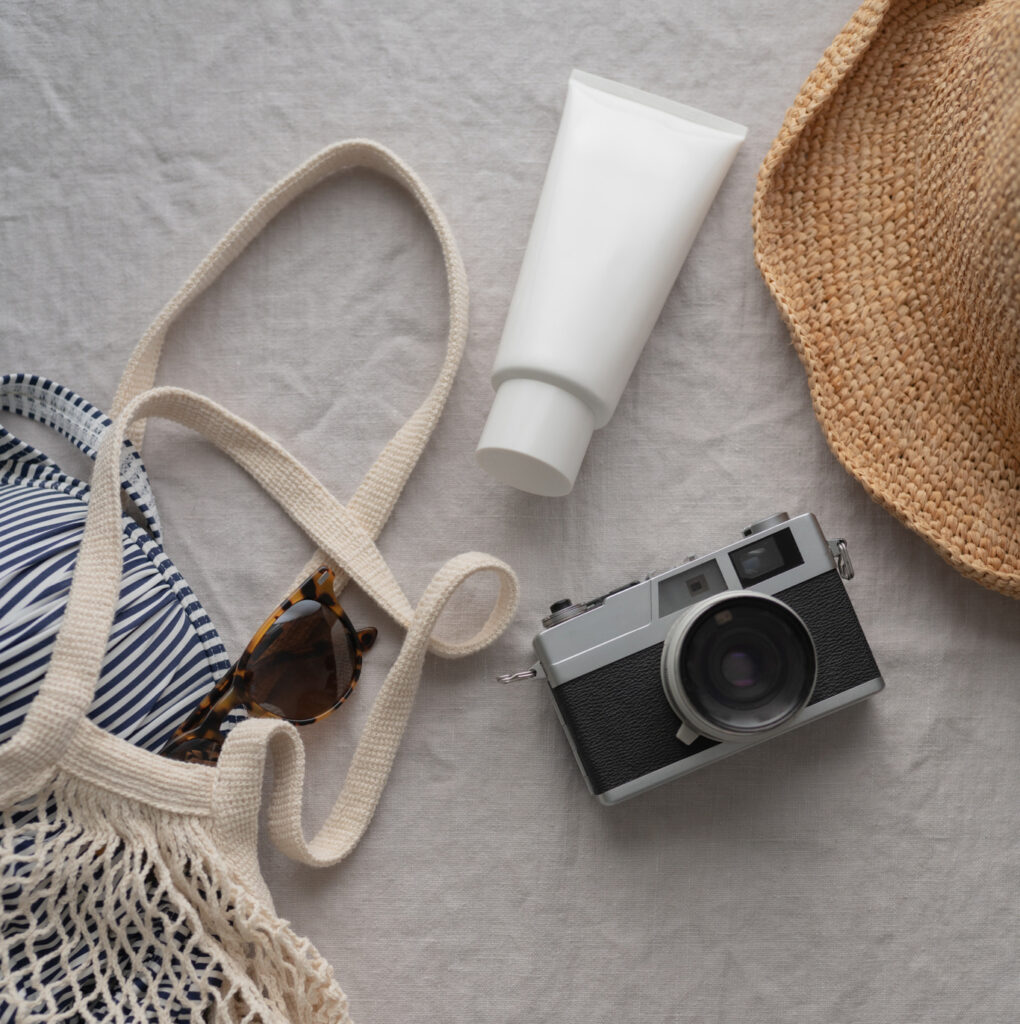 Ready for the beach, a stock photo featuring a vintage camera, sunglasses, swimsuit and hat, perfect stock image for your summer travel brands.