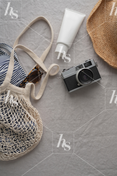 Flatlay of a vintage camera, sunscreen, and beach day accessories.