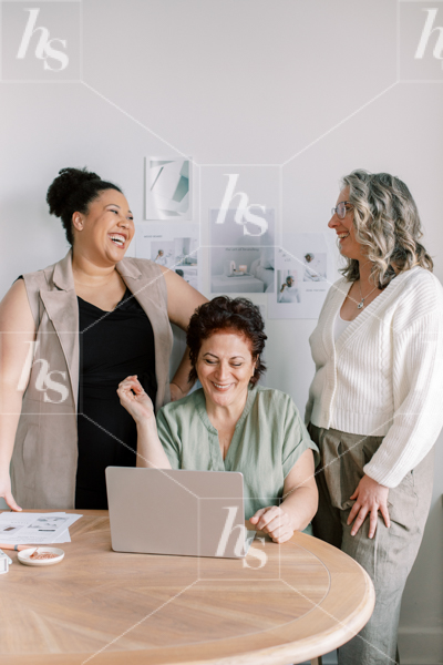 Team of diverse women laughing during meeting, a stock image of collaboration for business and career coaches.
