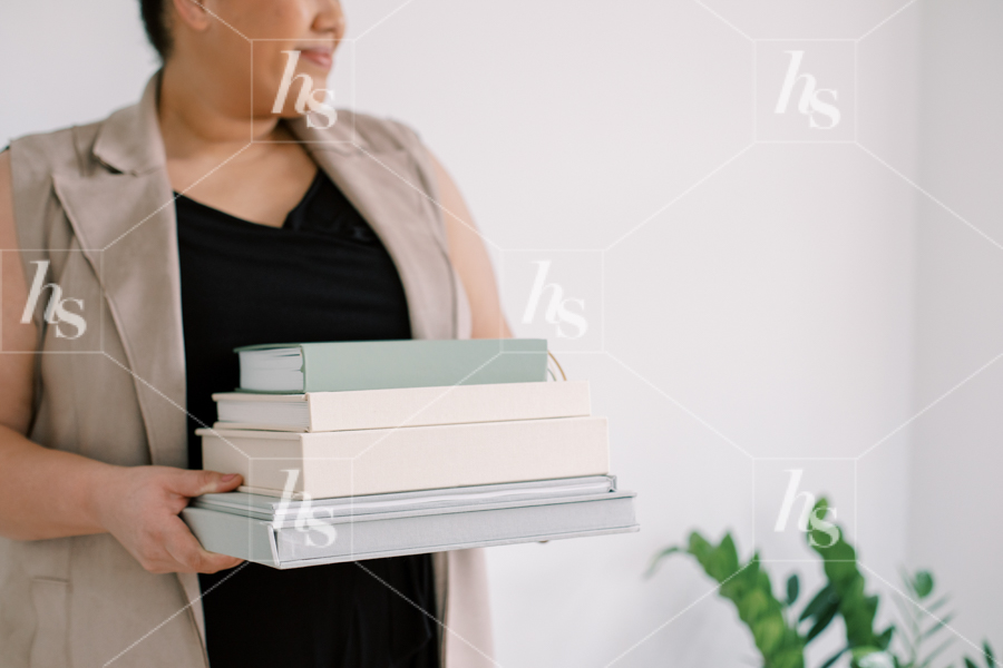 Stock photo of black woman holding stack of books, part of Co-Work workspace collection.