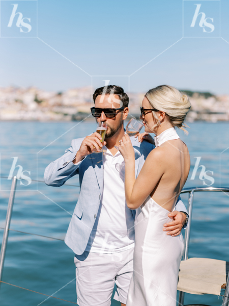 Stock image of a couple toasting on a yacht with the blue see in the background, perfect for lifestyle and travel brands