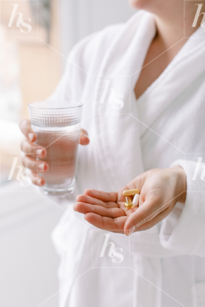 Woman holding water and vitamins in our latest collection of beauty and wellness stock photos. 