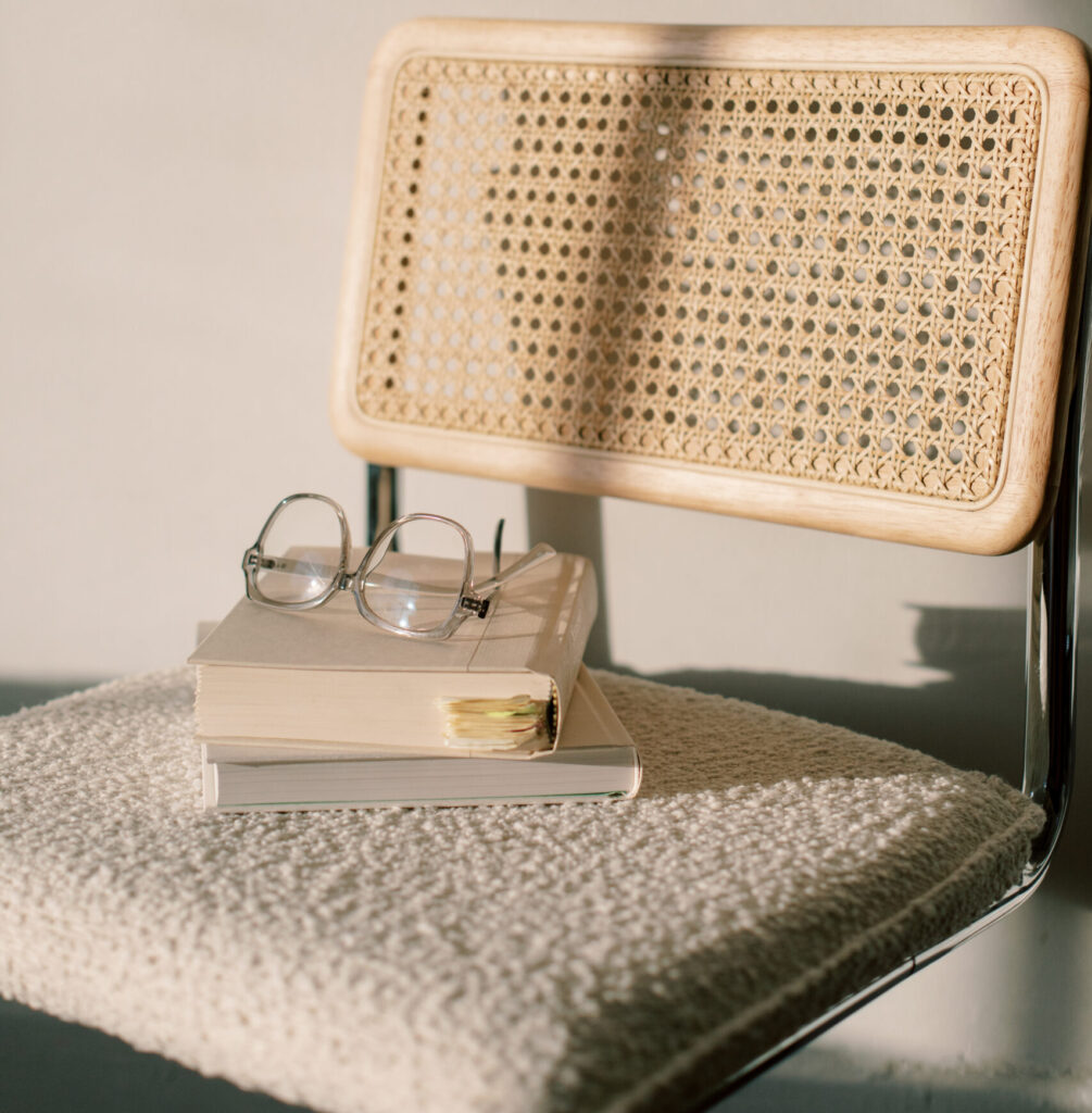 Books and reading glasses stacked on vintage chair, part of Haute stock's Artist's Corner collection