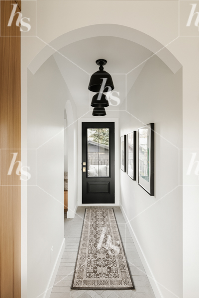 A stunning entry way with a black door, long rug and statement lighting. Download cozy interior stock photos for interior designers.