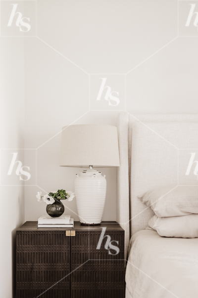 A white lamp on a side table next to a bed in this collection of cozy interior stock photos for entrepreneurs.