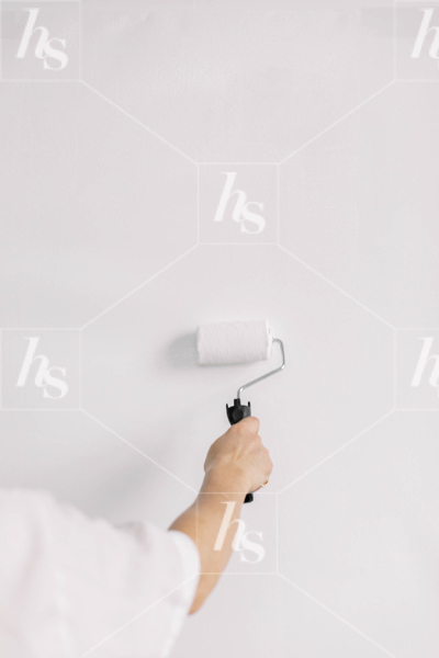 Minimal stock image of woman painting using a roller.
