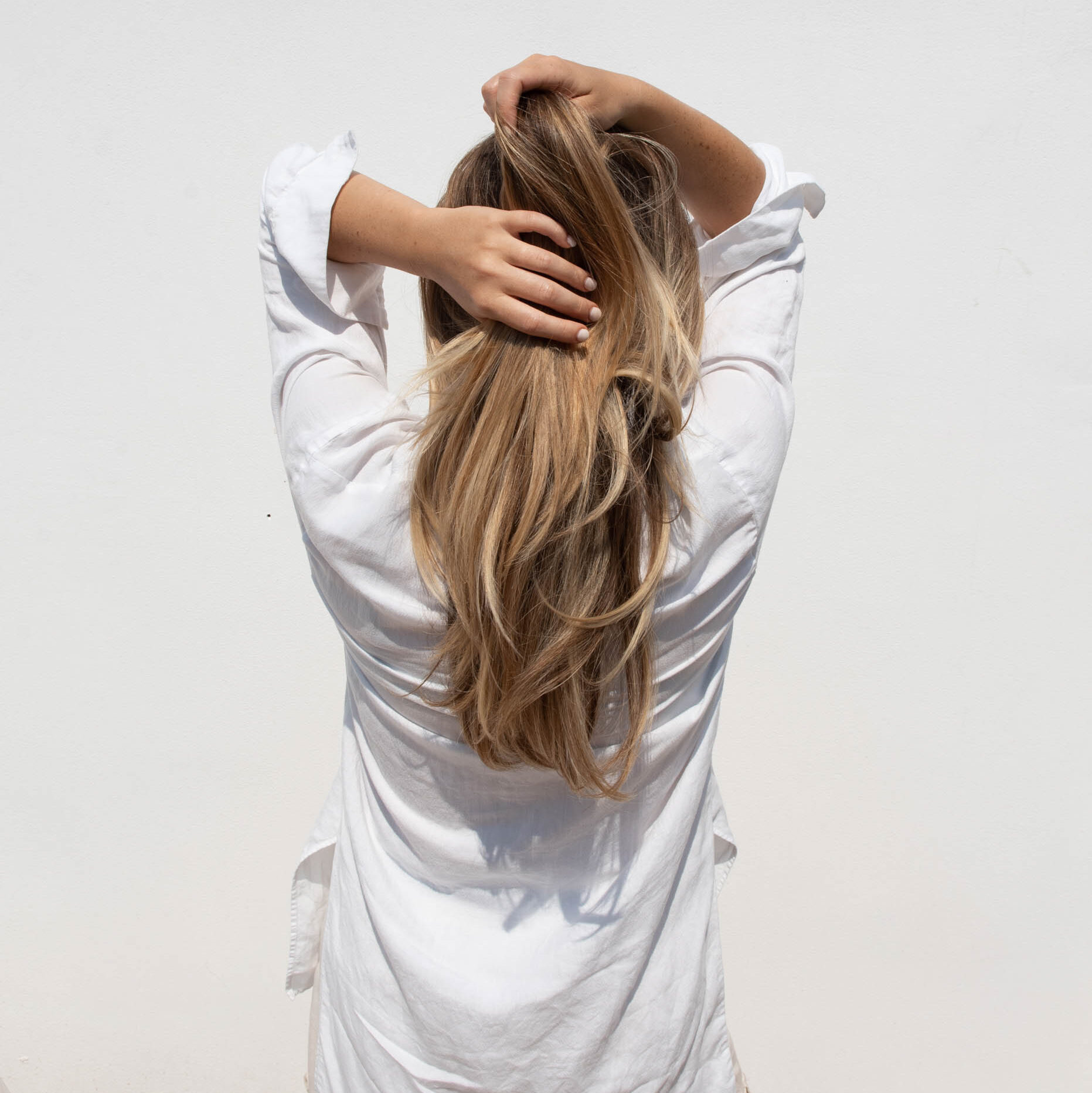 Woman running her hands through her long blonde hair. Elevate your brand with feminine Self-care stock and videos collection.