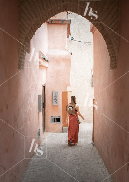 Perfect fall travel stock photo of a woman exploring a hidden Moroccan alleyway.