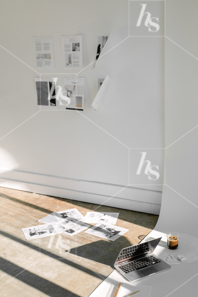 A scene showing a designer at work, with a vision board on the wall, papers on the floor, and a laptop and coffee on the floor, part of the studio collection of elevated workspace stock photos and videos