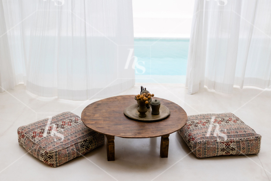 Tea and coffee table with cushion seating next to outdoor pool in traditional style, part of Bali interiors - earthy architecture stock imagery collection by Haute Stock