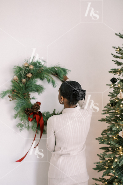Woman hanging a wreath, part of the holiday stock photos and videos collection by Haute Stock