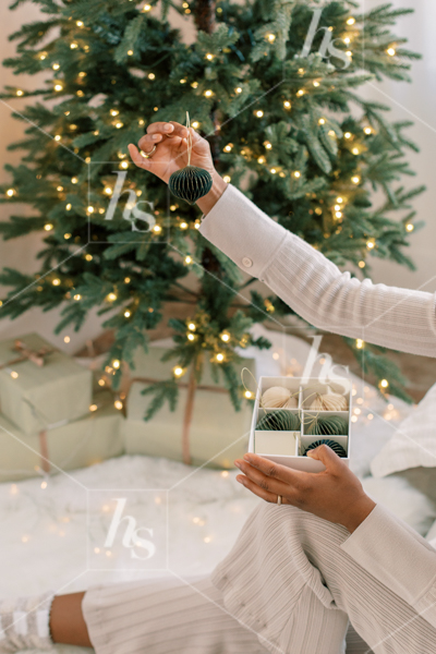 Woman holding a green ornament, decorating the Christmas tree: part of the holiday stock photos and videos collection by Haute Stock
