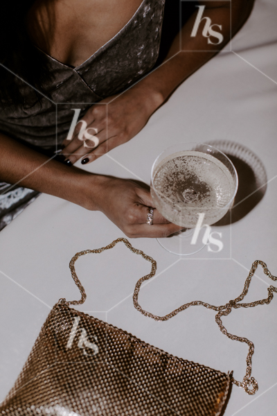 Overhead shot of woman in velvet dress holding onto champagne glass, part of Ladies night a moody NYE stock imagery collection.