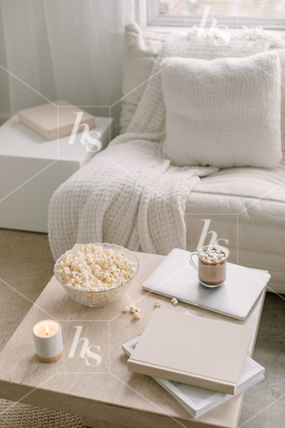 Cozy workspace scene with laptop, hot chocolate, books, candles, and a big bowl of popcorn, part of winter nights: workspace stock photos & videos collection