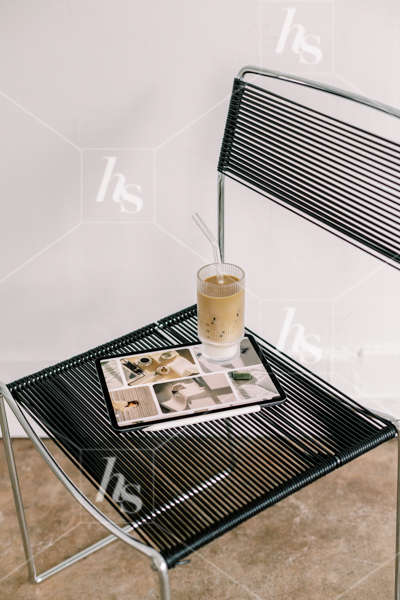 Iced coffee resting on top of iPad, on top of black chair in office, part of cool workspace stock photos and videos collection perfect for chill and creative entrepreneurs