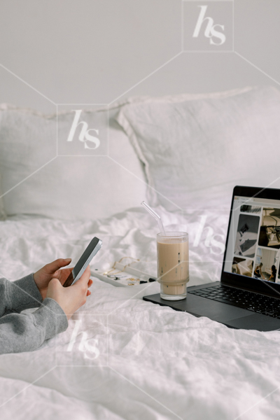 Woman scrolling on phone while working from bed, part of cool workspace stock photos and videos collection perfect for chill and creative entrepreneurs