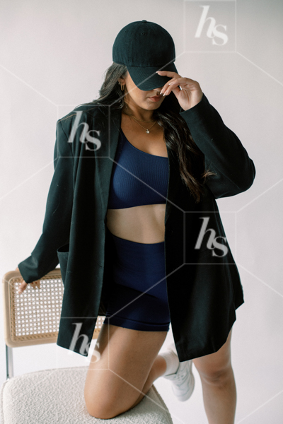 Woman posing in athleisure set, black blazer, and hat