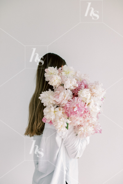 Woman facing away from the camera while holding a large bouquet of flowers, part of Haute Stock's Bed of Peonies, floral stock photos & videos collection.