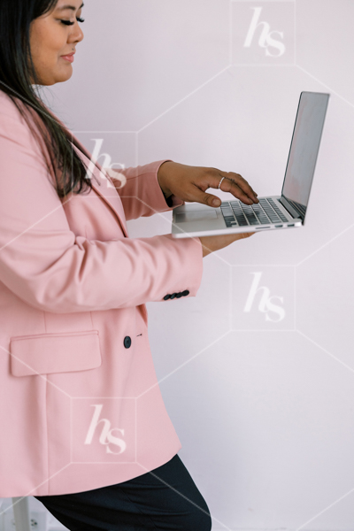 Woman in pink blazer, typing on laptop while standing part of Millennial pink: feminine workspace stock videos collection.