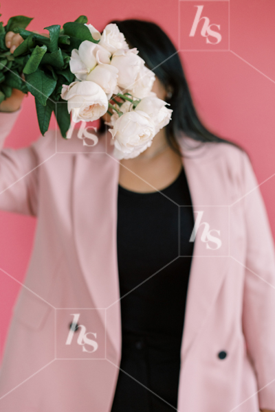 Woman  in pink blazer, is holding a bouquet of roses in front of her face, part of Millennial pink: feminine workspace stock videos collection.