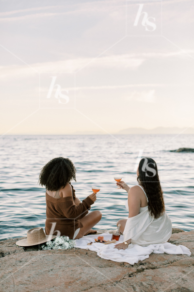 Friends enjoying each other's company at a beach picnic, part of Sips at Sunset a fun stock photos & videos collection by Haute Stock